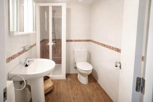 a white bathroom with a toilet and a sink at San Lorenzo House in Gijón