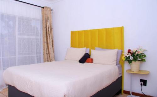 a bedroom with a large bed with a yellow headboard at Wakanda in Johannesburg