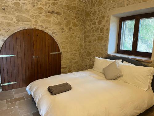 a bedroom with a large white bed and a window at Vineyard Farmhouse in Massignano in Massignano