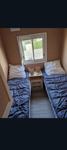 two beds in a small room with a window at Mobilhome spacieux in Pornic