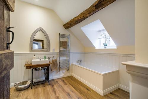 a bathroom with a tub and a sink and a window at 3 Bed in Callaughton oc-b34809 in Much Wenlock