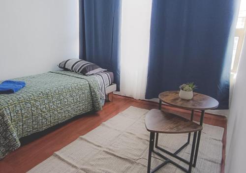a bedroom with a table and a bed and a table and stool at Departamentos Home Bulnes in Santiago