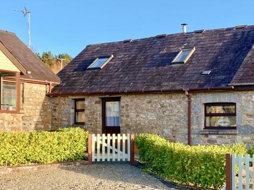 a stone house with a wooden fence in front of it at The Nook in Amroth