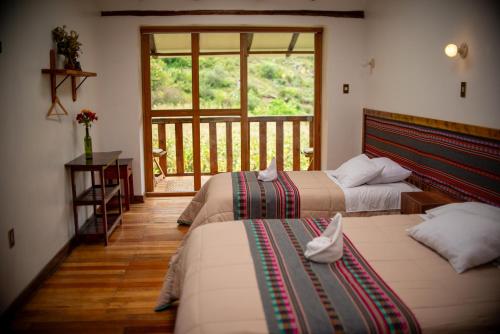 two beds in a room with a balcony at Casita Huaran in Calca