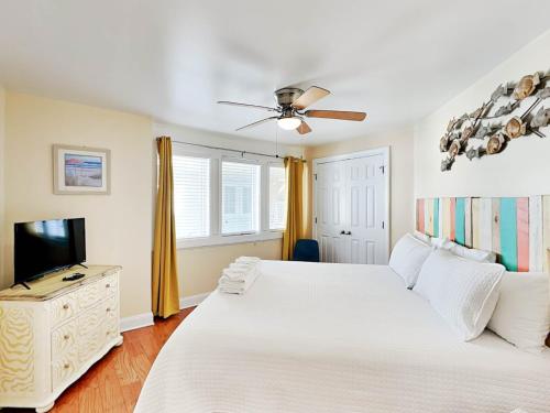 a white bedroom with a bed and a tv at Captains Watch 11 in Tybee Island