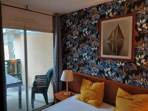 a bedroom with a bed and a picture of a sailboat on the wall at Appartement Carcans Maubuisson in Carcans