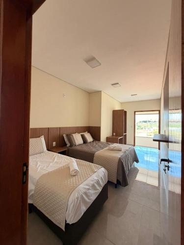 a hotel room with two beds and a pool at Fonsecas House Suíte Privativas in Paraguaçu