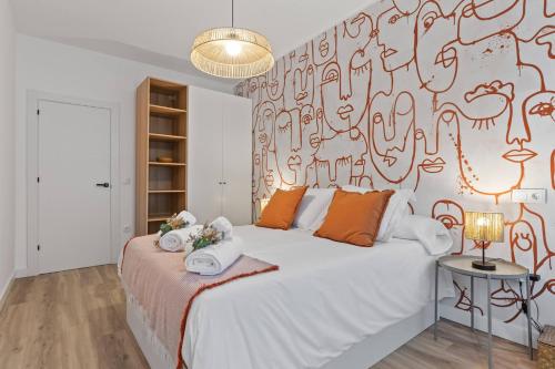 a bedroom with a large white bed with orange pillows at Picasso, para 6 personas, espacioso piso de diseño in Gijón