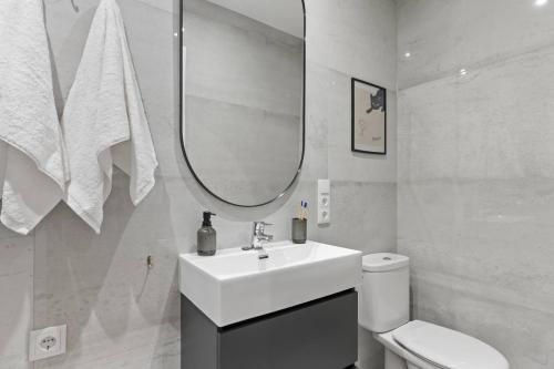 a white bathroom with a sink and a mirror at Picasso, para 6 personas, espacioso piso de diseño in Gijón