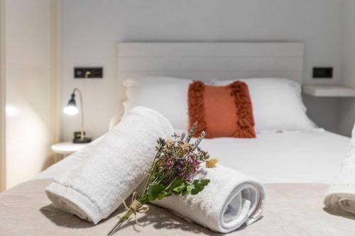 a bedroom with a bed with towels and flowers on it at Plaza del Carmen in Gijón