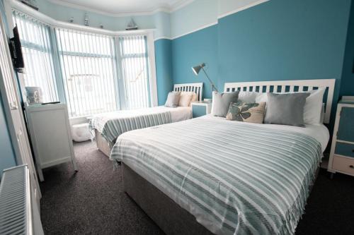 a bedroom with two beds with blue walls and windows at The Gables Hotel by Cherish Lewis Blackpool in Blackpool