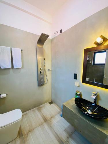 a bathroom with a sink and a toilet and a mirror at The Galaxy Airport Hotel in Negombo