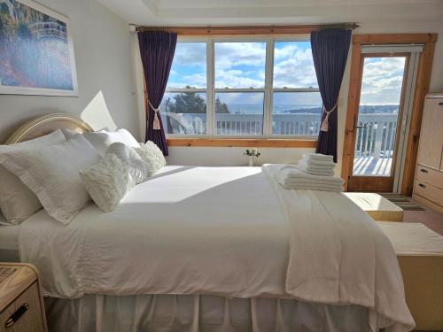 a bedroom with a large white bed with a window at Panoramic Sunrise House in Terence Bay
