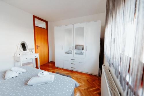 a white bedroom with a bed and a dresser at Apartman Deja vu in Livno