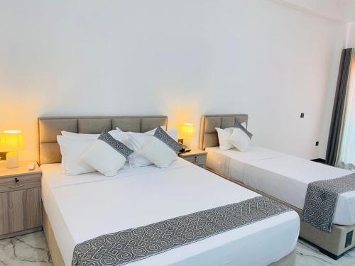 two white beds in a room with two lamps at The Galaxy Airport Hotel in Negombo