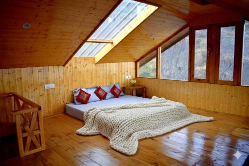 a bedroom with a bed in a room with windows at Top Mountain Mist Near Jibhi in Banjār