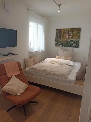 a small bedroom with a bed and a chair at Casa Stetten in Lörrach