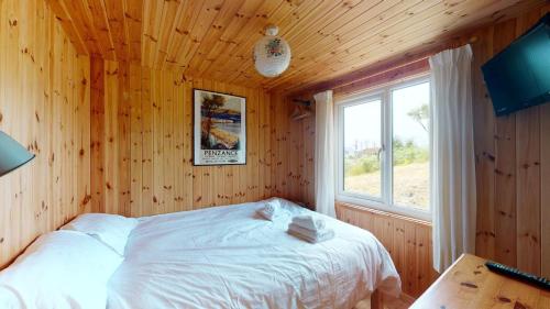 a bedroom with a bed in a wooden room with a window at F67 Ischia, Riviere Towans in Hayle