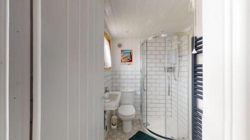 a white bathroom with a toilet and a shower at F67 Ischia, Riviere Towans in Hayle
