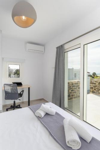 a bedroom with a bed and a desk and a window at Naxos Cube Villa Panoramic Views Maisonette with Sea View 2 min walk to Plaka Beach in Plaka