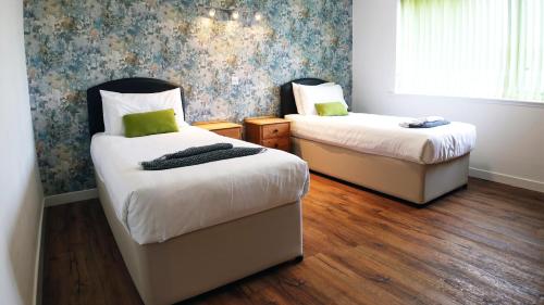 two beds in a room with wooden floors at Tigh Na Sith in Aultbea
