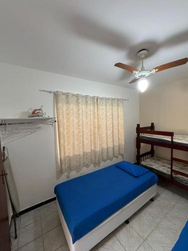 a bedroom with a blue bed and a ceiling fan at CasaPraiaSol1 in Rio das Ostras