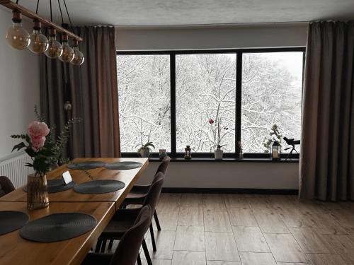 a dining room with a table and a large window at Cabana Dintre Fagi in Poiana Mărului