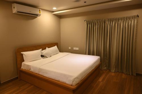 a bedroom with a bed with white sheets and a window at Haraa Suites Tiruvannamalai in Tiruvannāmalai
