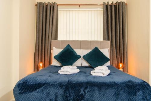 a bedroom with a blue bed with towels on it at Warrington Suites by Relax Stays in Warrington