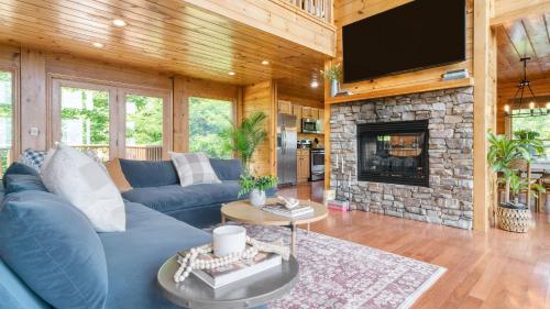 a living room with a blue couch and a stone fireplace at HotTub Sauna Pool Table Views Mins to Downtown Gatlingburg Hollows Haven in Gatlinburg
