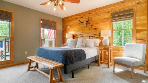 a bedroom with a bed and a chair and windows at HotTub Sauna Pool Table Views Mins to Downtown Gatlingburg Hollows Haven in Gatlinburg