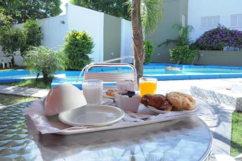 a tray of breakfast food on a table near a pool at Hotel Termal Emperatriz in Termas de Río Hondo