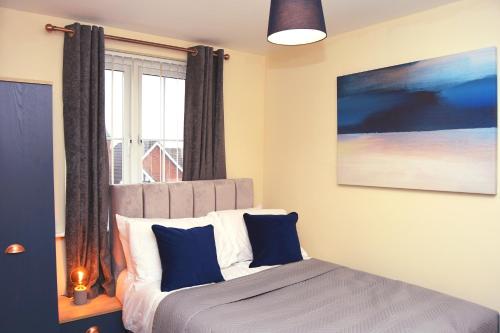 a bedroom with a bed with blue pillows and a window at Warrington Suites by Relax Stays in Warrington