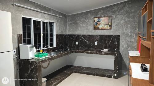 a bathroom with black marble walls and a window at Casa aconchegante em Sinop in Sinop