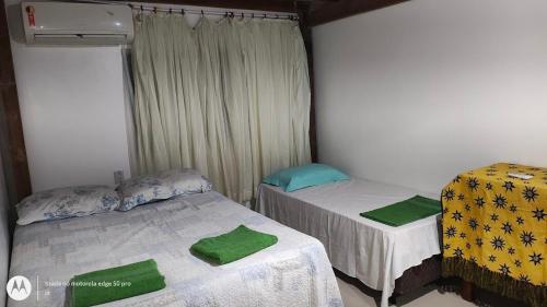 a bedroom with two beds with green towels on them at Casa aconchegante em Sinop in Sinop
