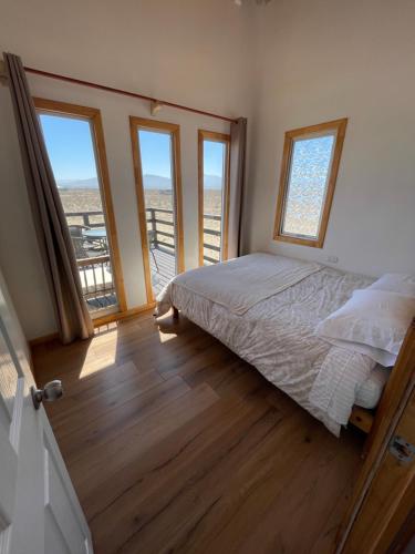 a bedroom with a bed and some windows at Rincon del desierto lodge in Punta de Choros