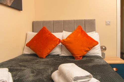 two orange pillows sitting on top of a bed at Warrington Suites by Relax Stays in Warrington