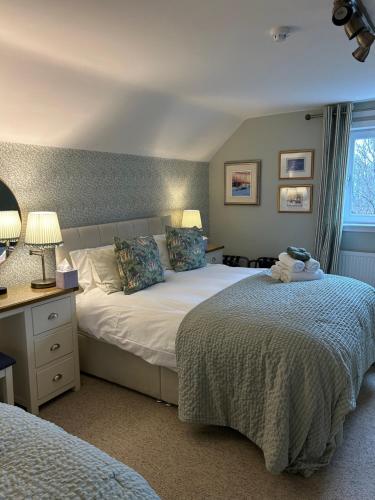 a bedroom with two beds and a desk with lamps at Castlecroft Bed and Breakfast in Stirling
