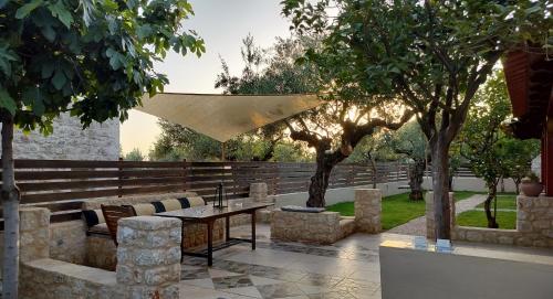a patio with a table and chairs and trees at Georges Houses Mani in Riglia