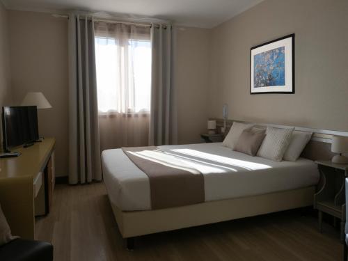 a hotel room with a bed and a window at Hotel Les Oliviers in Fayence