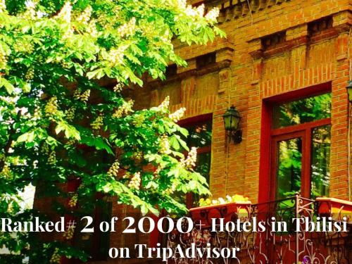 a tree next to a brick building with a window at Hotel British House in Tbilisi City