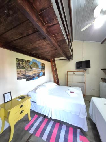 a bedroom with two beds and a desk and a television at Pousada Casa Rosa in Itacaré