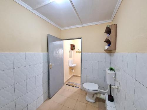 a bathroom with a toilet and a shower and a door at Janari Homes in Diani Beach