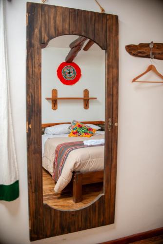 a mirror on a wall with a bed in a room at Casita Huaran in Calca