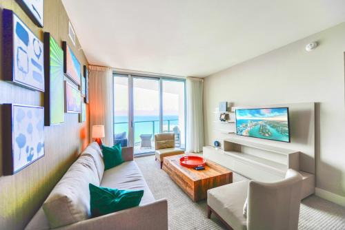a living room with a couch and a tv at Oceanfront Escape - Rooftop Pool & Beach Access in Hollywood
