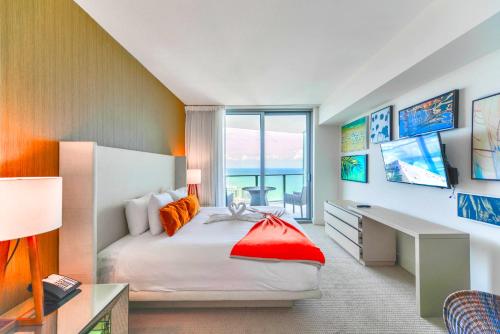 a bedroom with a bed with a desk and a window at Oceanfront Escape - Rooftop Pool & Beach Access in Hollywood