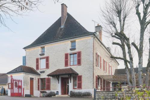 an old brick house with red windows and a black roof at Logis Hostellerie la Chaumière in Arsonval