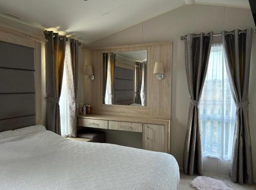 a bedroom with a white bed and a mirror at Caravan by the beach in Kinmel Bay