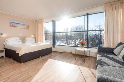 a large bedroom with a bed and a couch at Hotel Tammsaare Full Automated Hotel in Pärnu