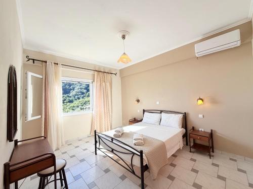 a bedroom with a bed and a table and a window at Galini Seaview Kontogialos in Pelekas